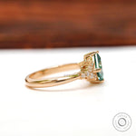 Side profile view of the green moissanite engagement ring with diamonds.