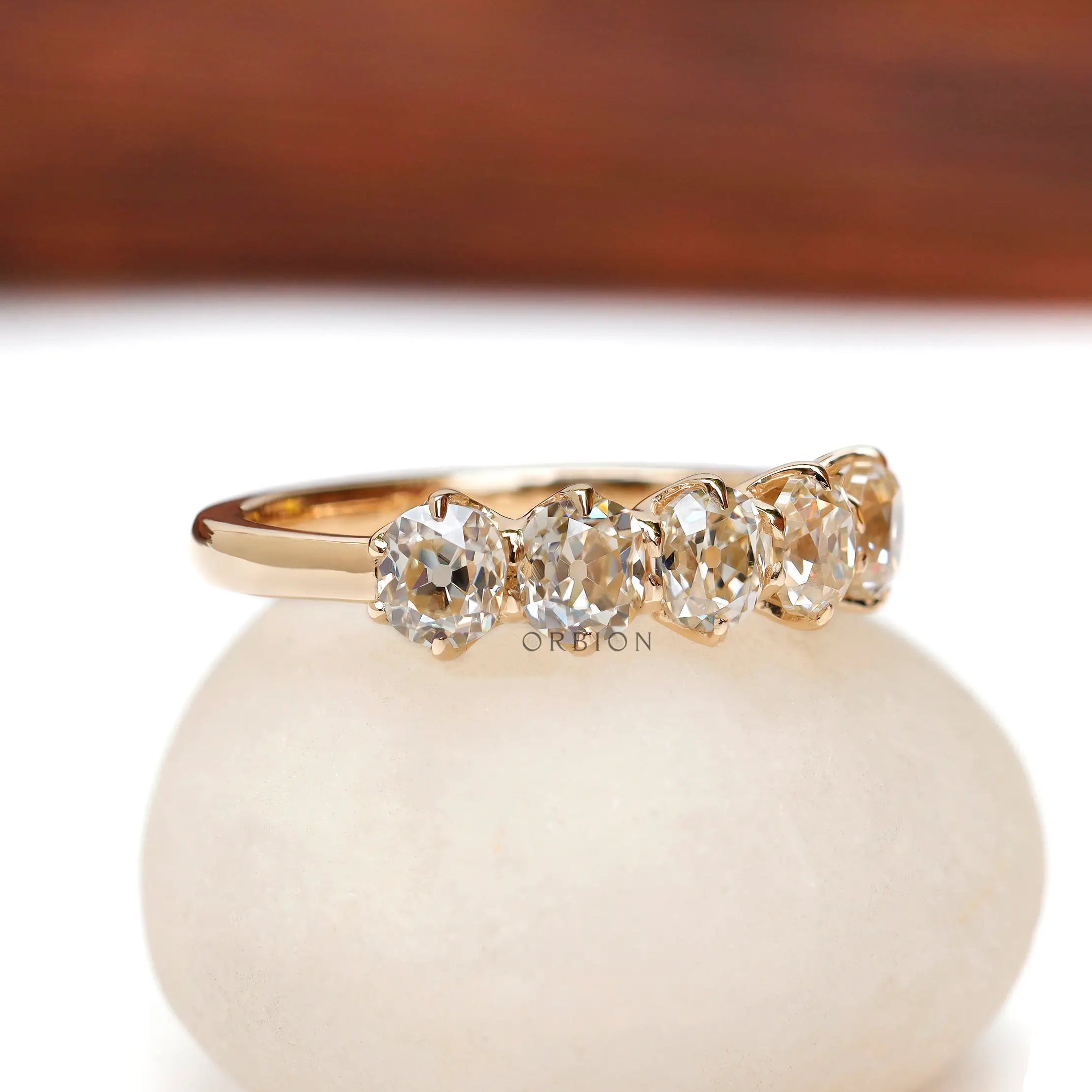 Angled view showing five cushion moissanites in yellow gold band