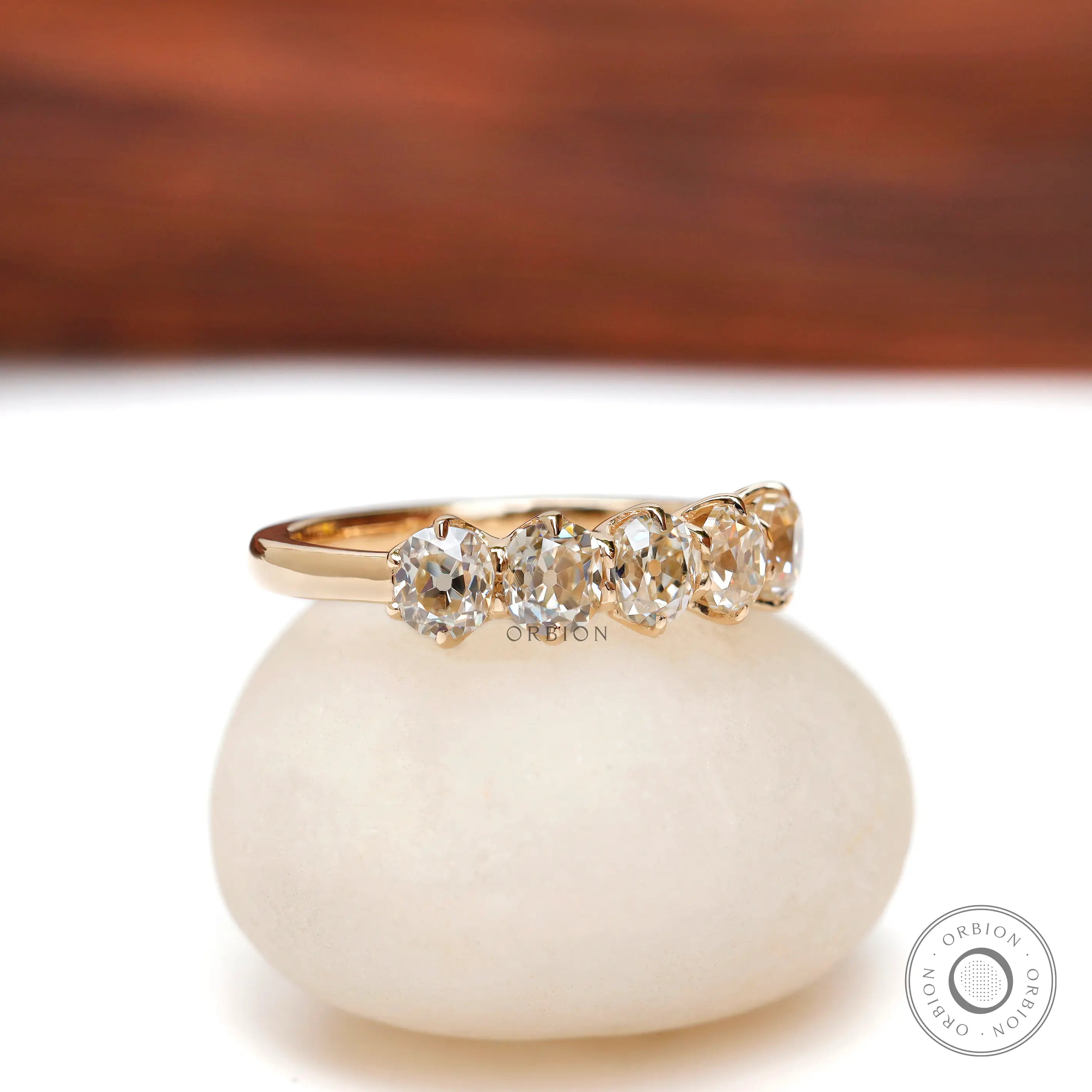 Angled view showing five cushion moissanites in yellow gold band