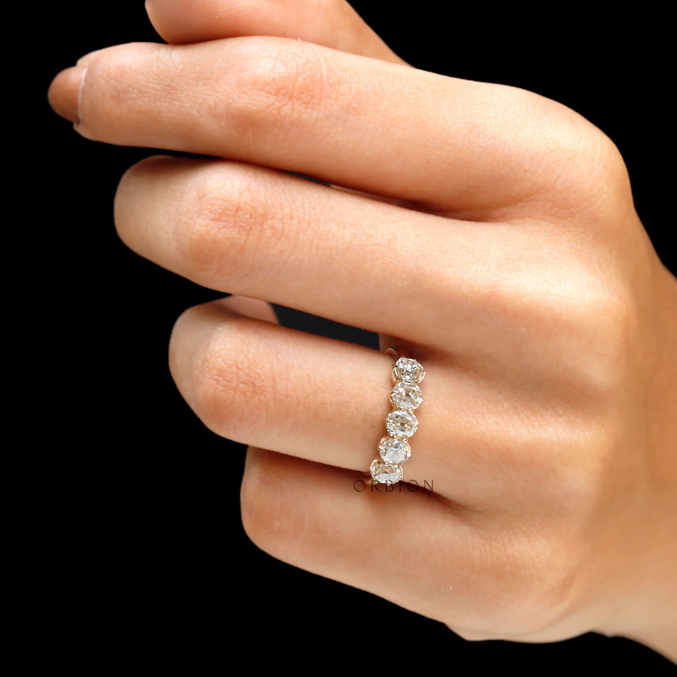 On-hand side view showing scalloped prongs and sparkle across the band