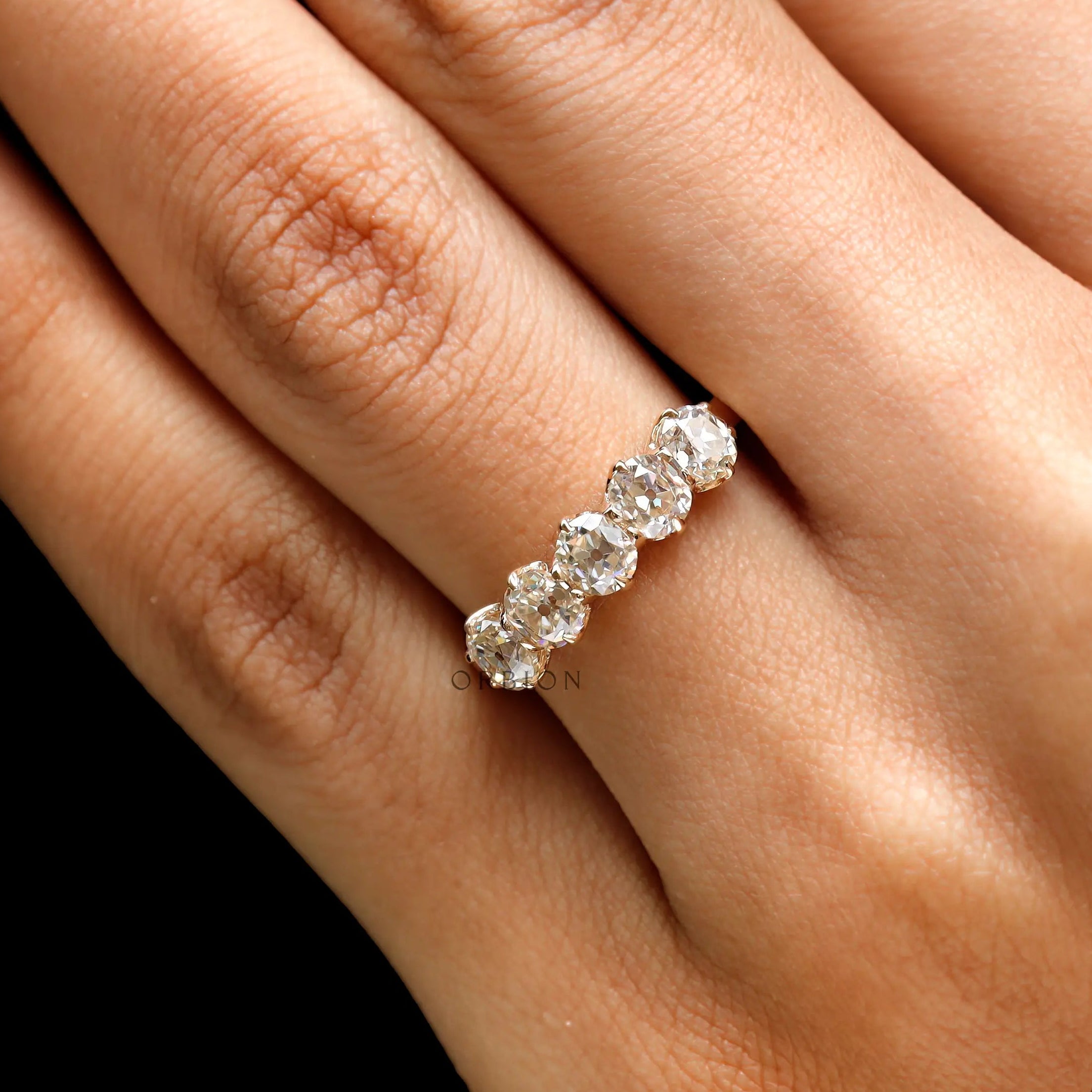 Lifestyle on-hand photo of five stone moissanite wedding band in yellow gold