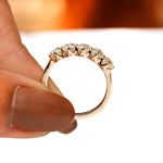 Profile close-up of five stone moissanite band held between fingers
