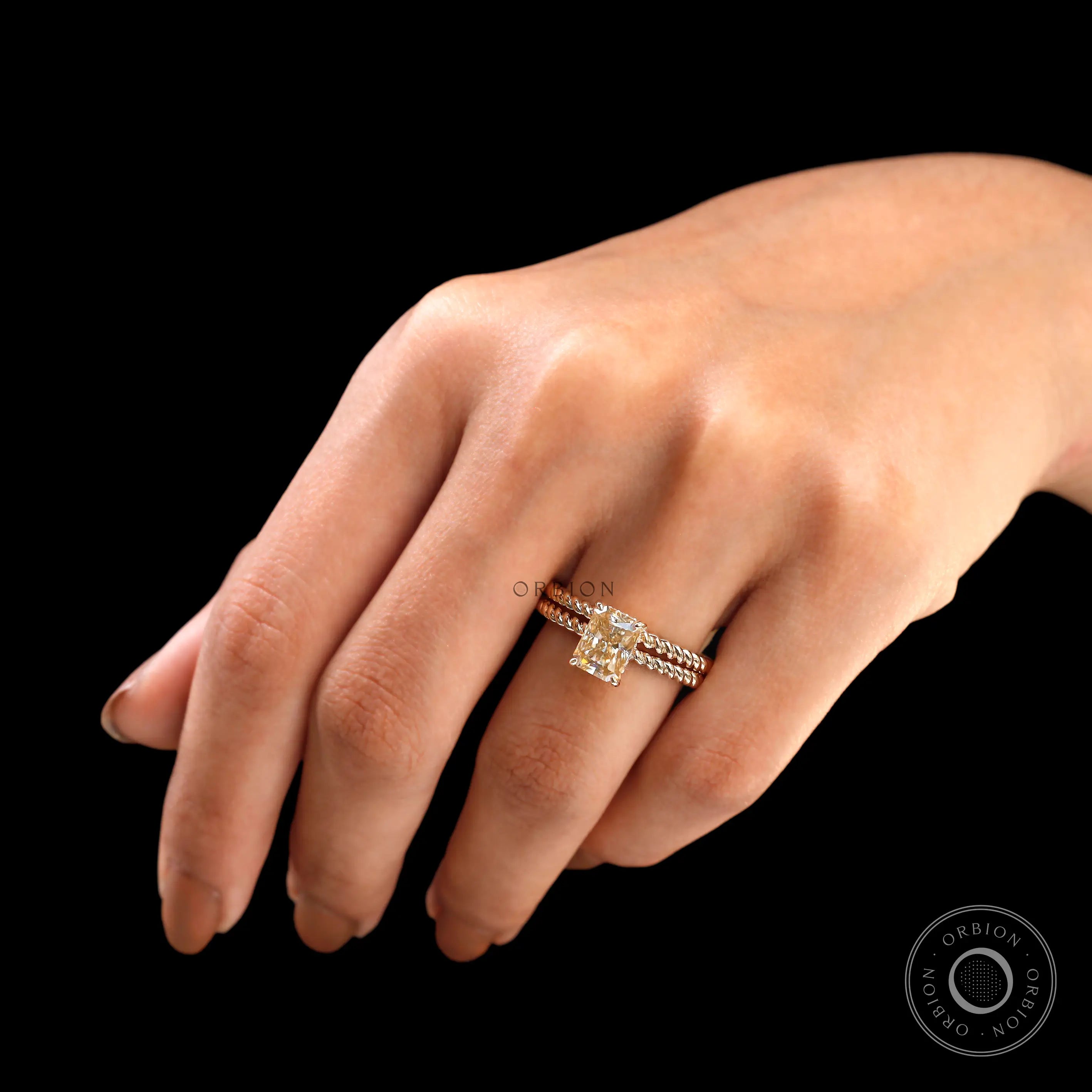 Radiant champagne moissanite ring with hidden halo on finger close-up