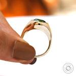 Close-up of blue green oval moissanite in bezel signet setting