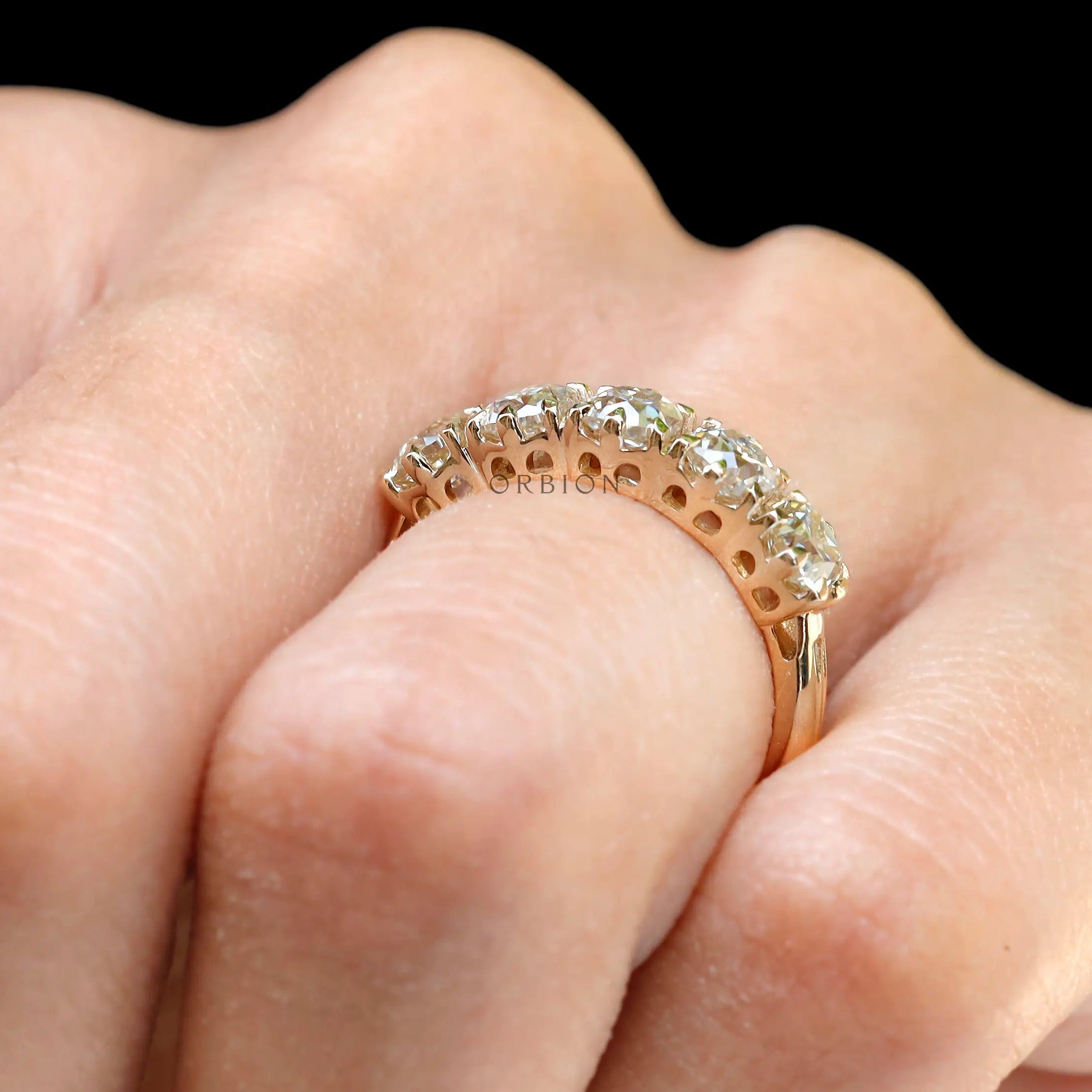 Close-up of five stone moissanite band showcasing vintage prong setting