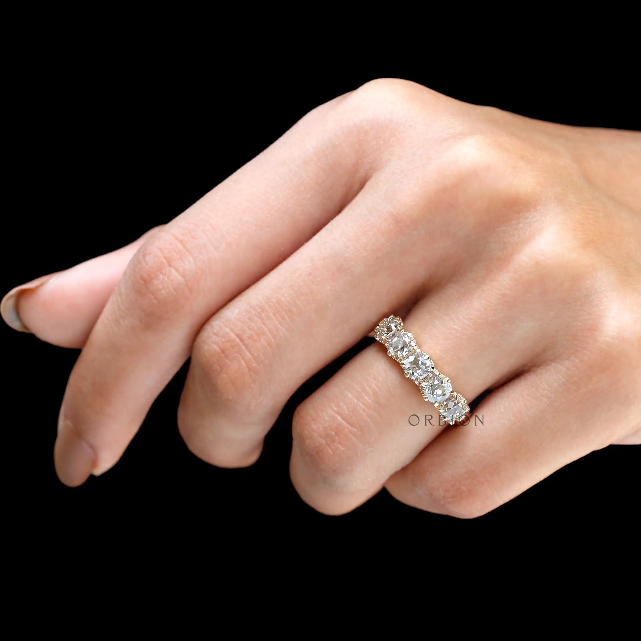 Lifestyle image of vintage five stone moissanite wedding band on finger