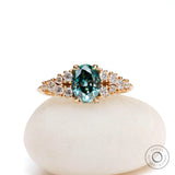 Oval blue green moissanite cluster ring in yellow gold