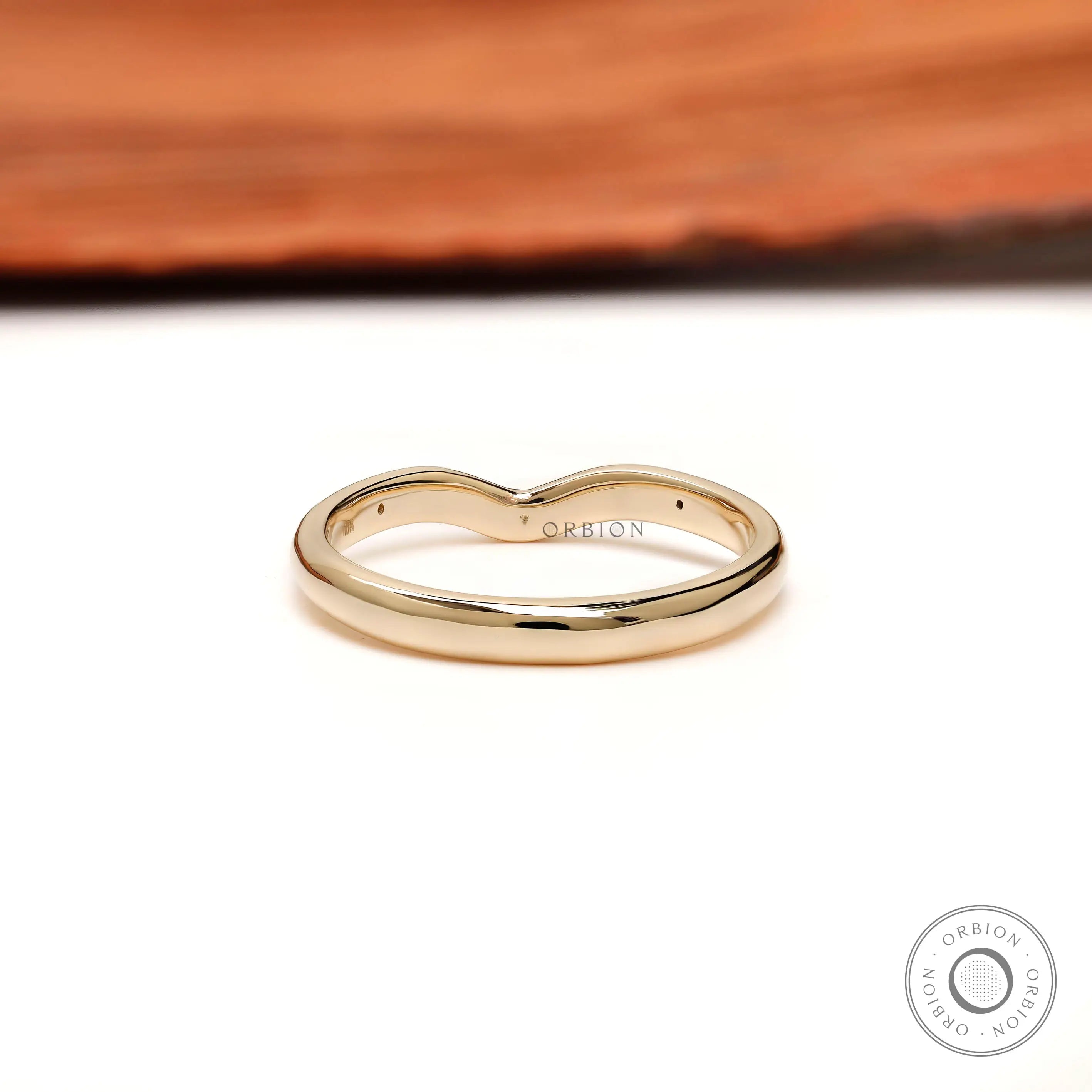 Back view of curved nesting wedding band with starburst details on both shoulders.