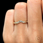 On-hand lifestyle image of starburst curved band styled as a stacking ring.