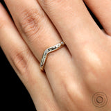 Close-up on finger of curved wedding band highlighting starburst sparkle.