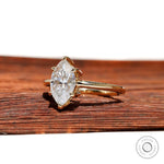 Angled view showing marquise moissanite sparkle and slim yellow gold band.