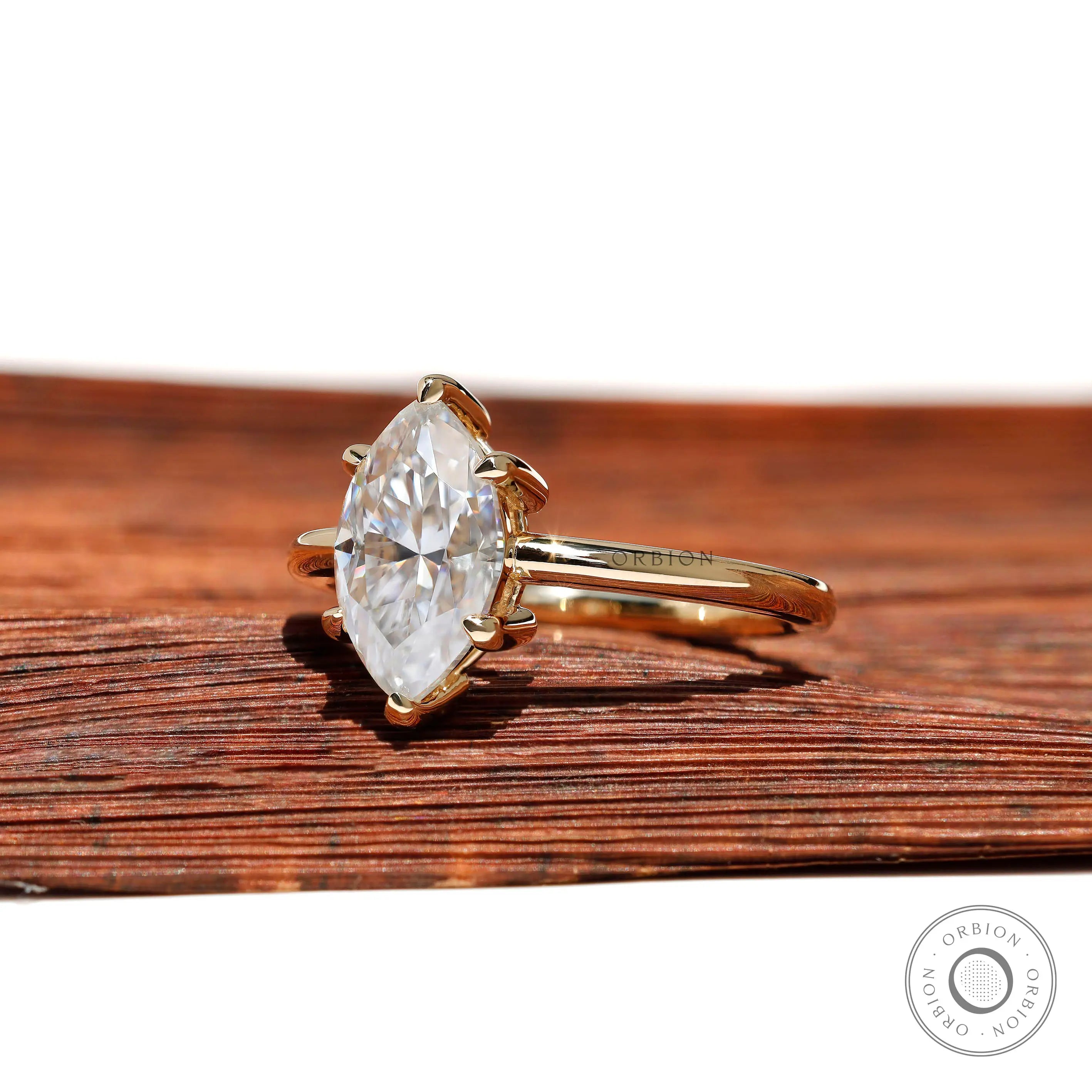 Angled view showing marquise moissanite sparkle and slim yellow gold band.