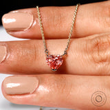 Scale view of pink heart pendant across fingers on fine gold chain