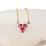 Front view of pink heart diamond pendant on white display stone