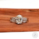 Elongated Cushion Moissanite ring set with brilliant side stones in 10K white gold, on a textured wooden surface