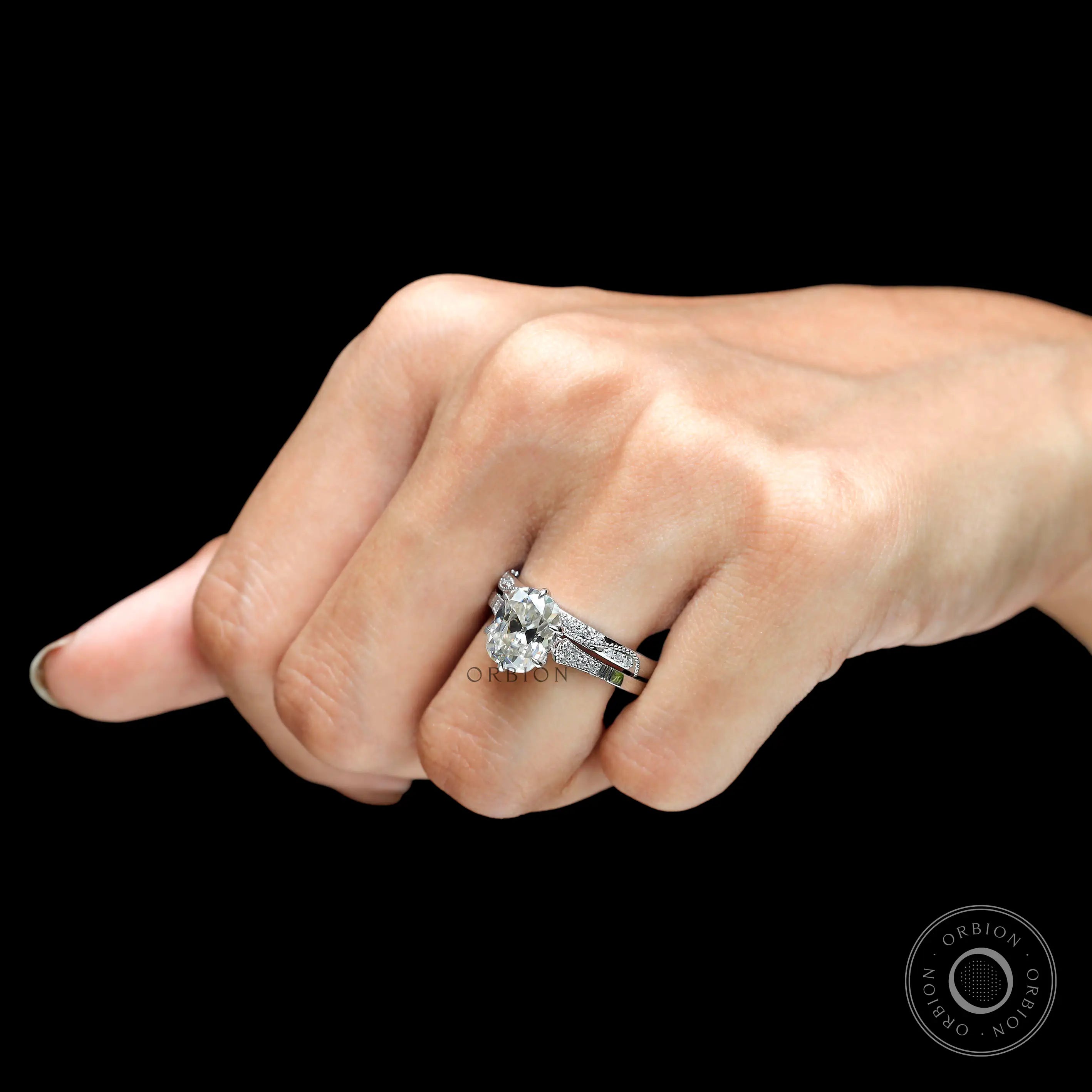 Top-down view of the elongated cushion Moissanite ring with side stones, on a white backdrop.