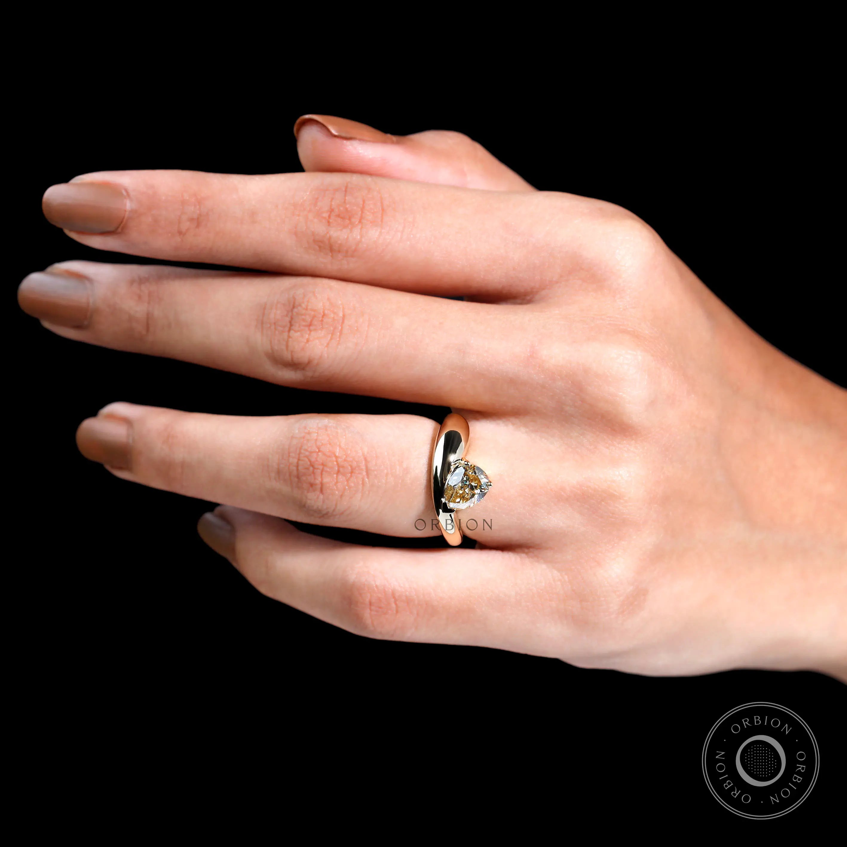Close-up of bold gold band and pear-cut moissanite