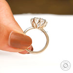 Close side detail of open tulip prongs supporting large round center stone.
