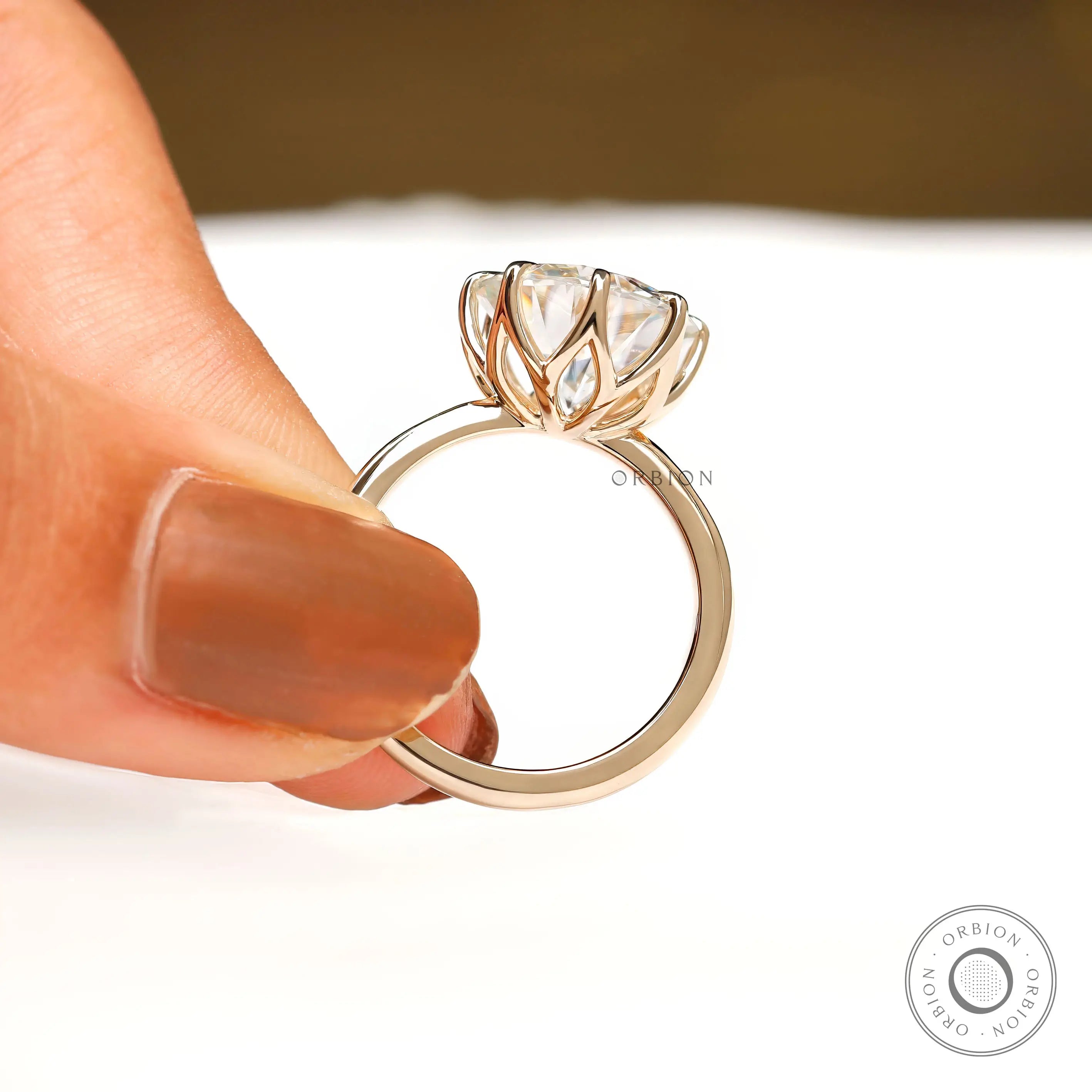 Close side detail of open tulip prongs supporting large round center stone.