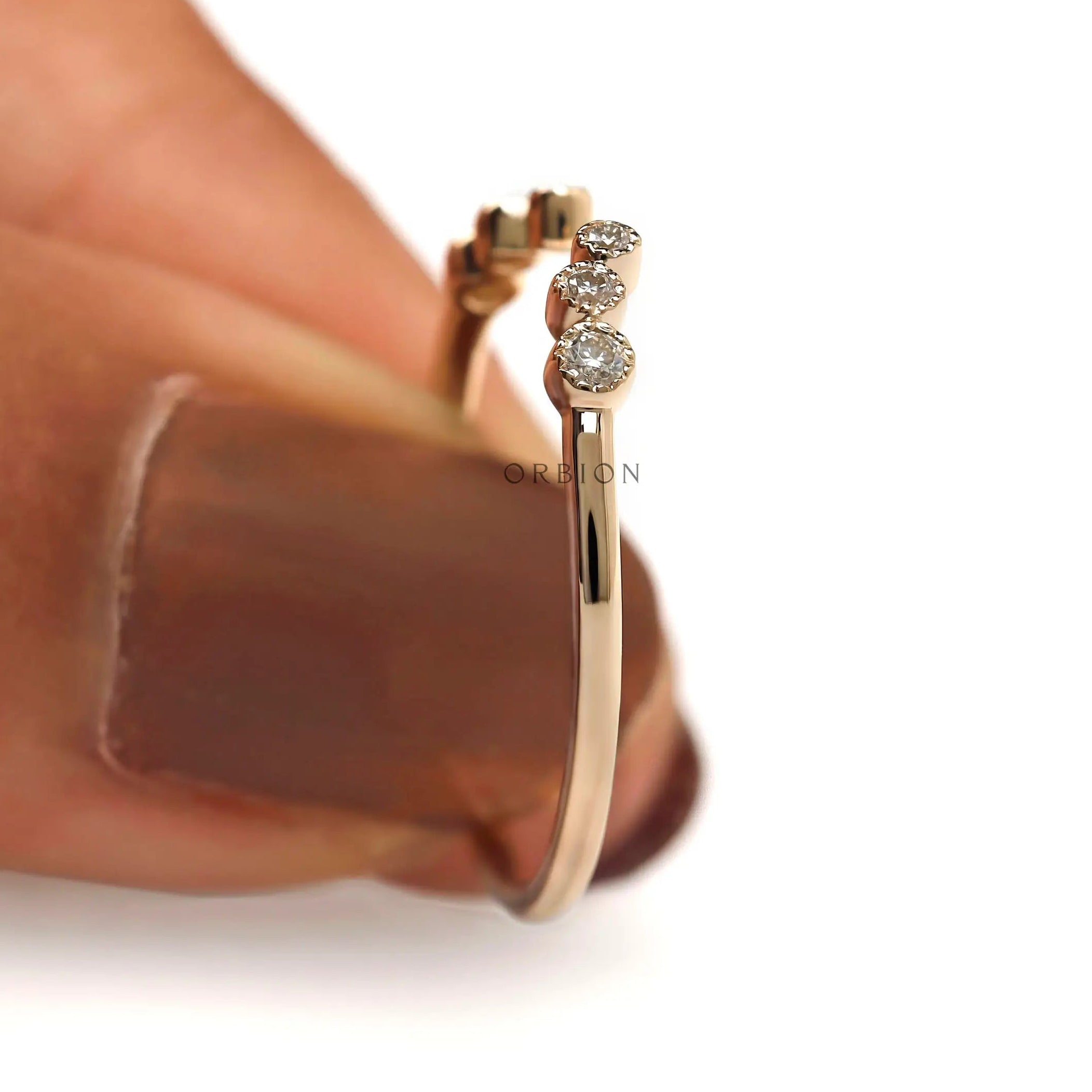 Close-up of round diamond trio on open curved wedding band