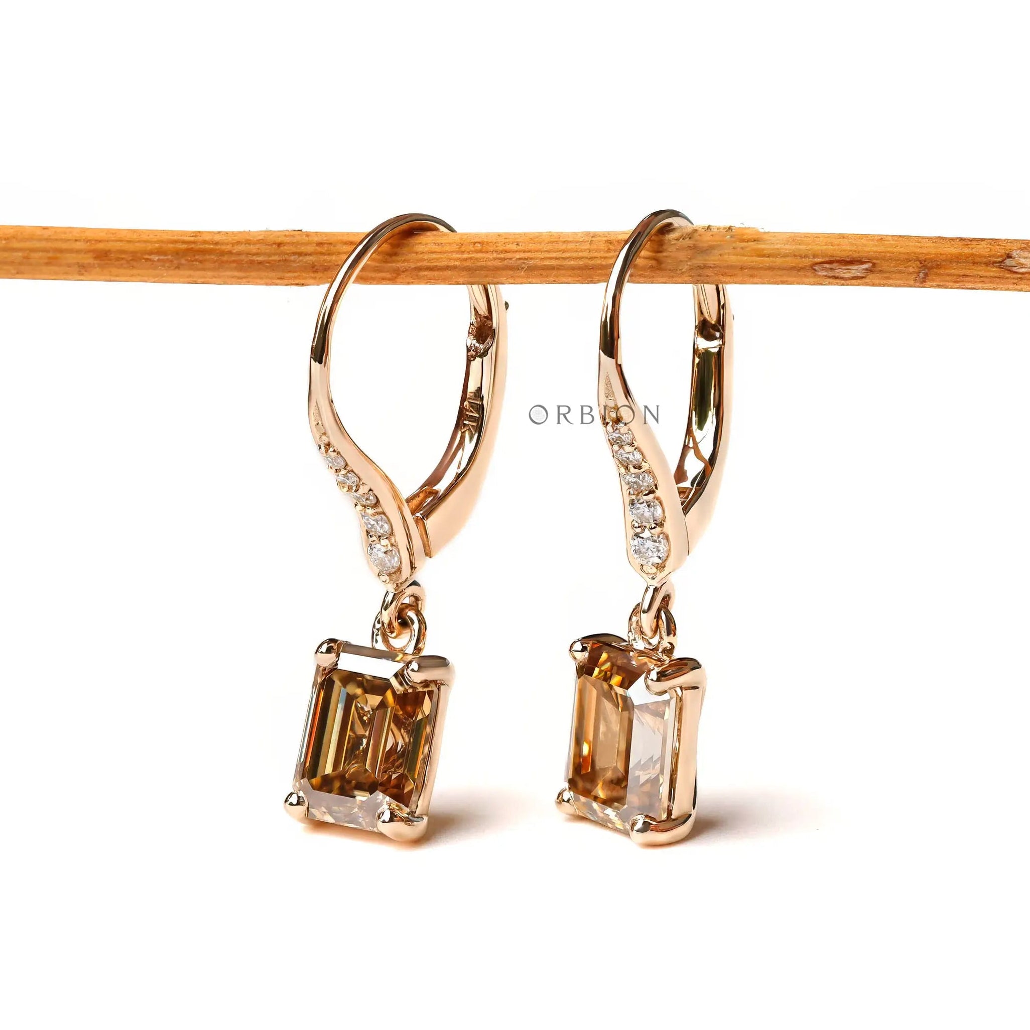 Emerald cut champagne moissanite drop earrings with round diamond accents yellow gold
