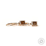 Yellow gold dangling earrings with step cut emerald champagne moissanite close up