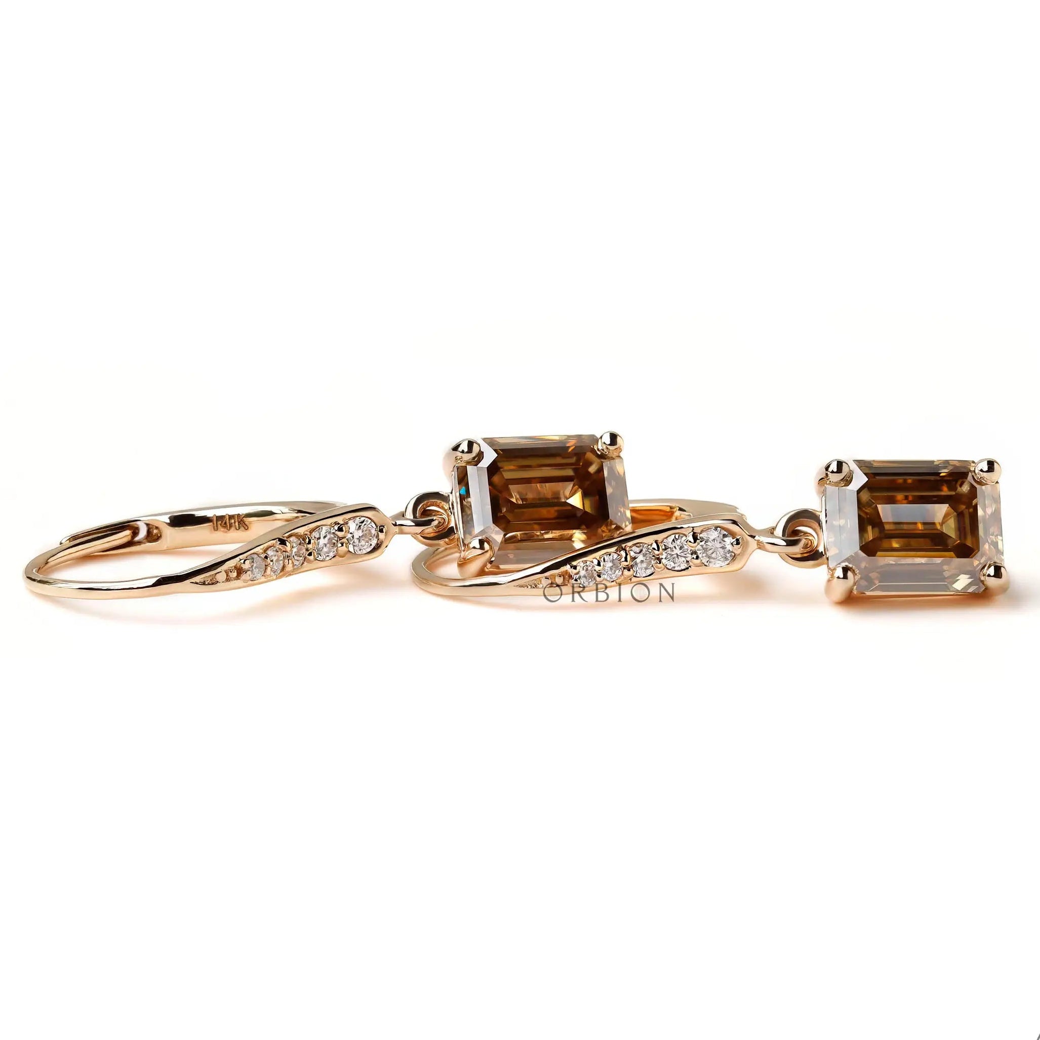 Yellow gold dangling earrings with step cut emerald champagne moissanite close up