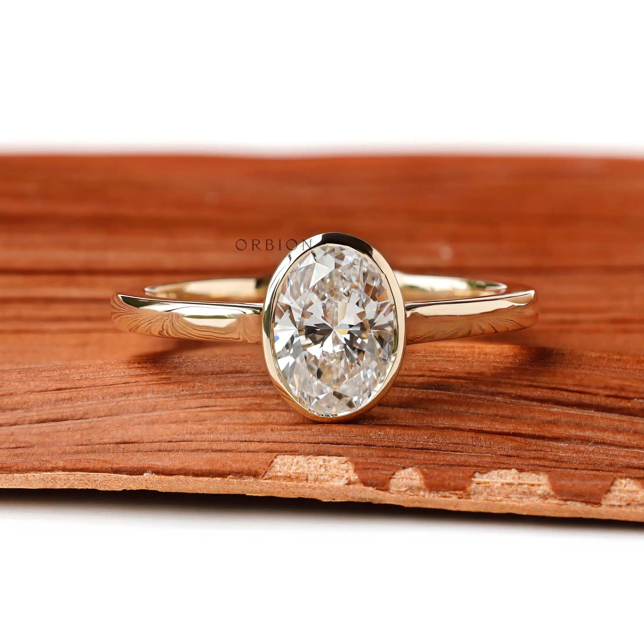 Oval lab diamond bezel ring front view on wood