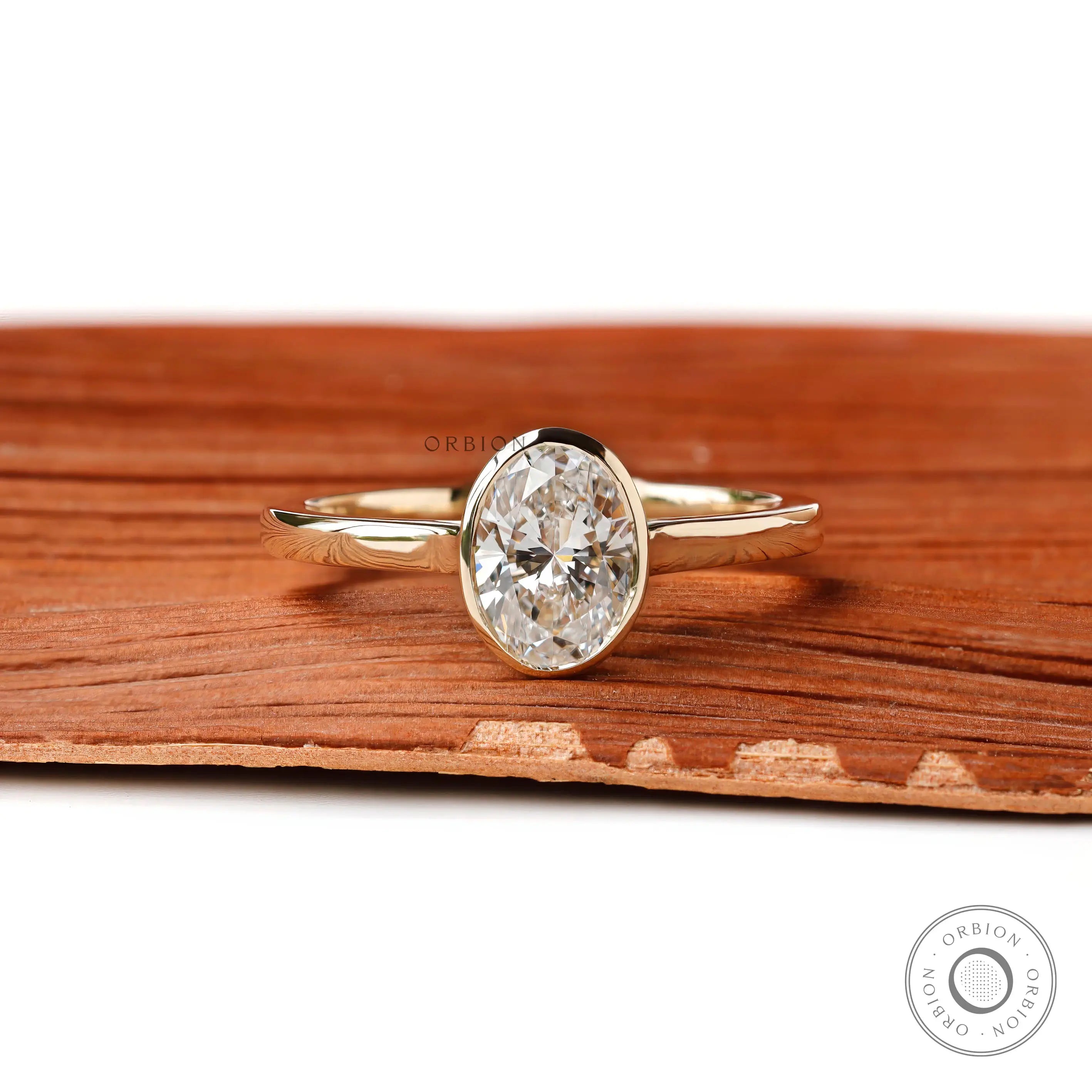 Oval lab diamond bezel ring front view on wood