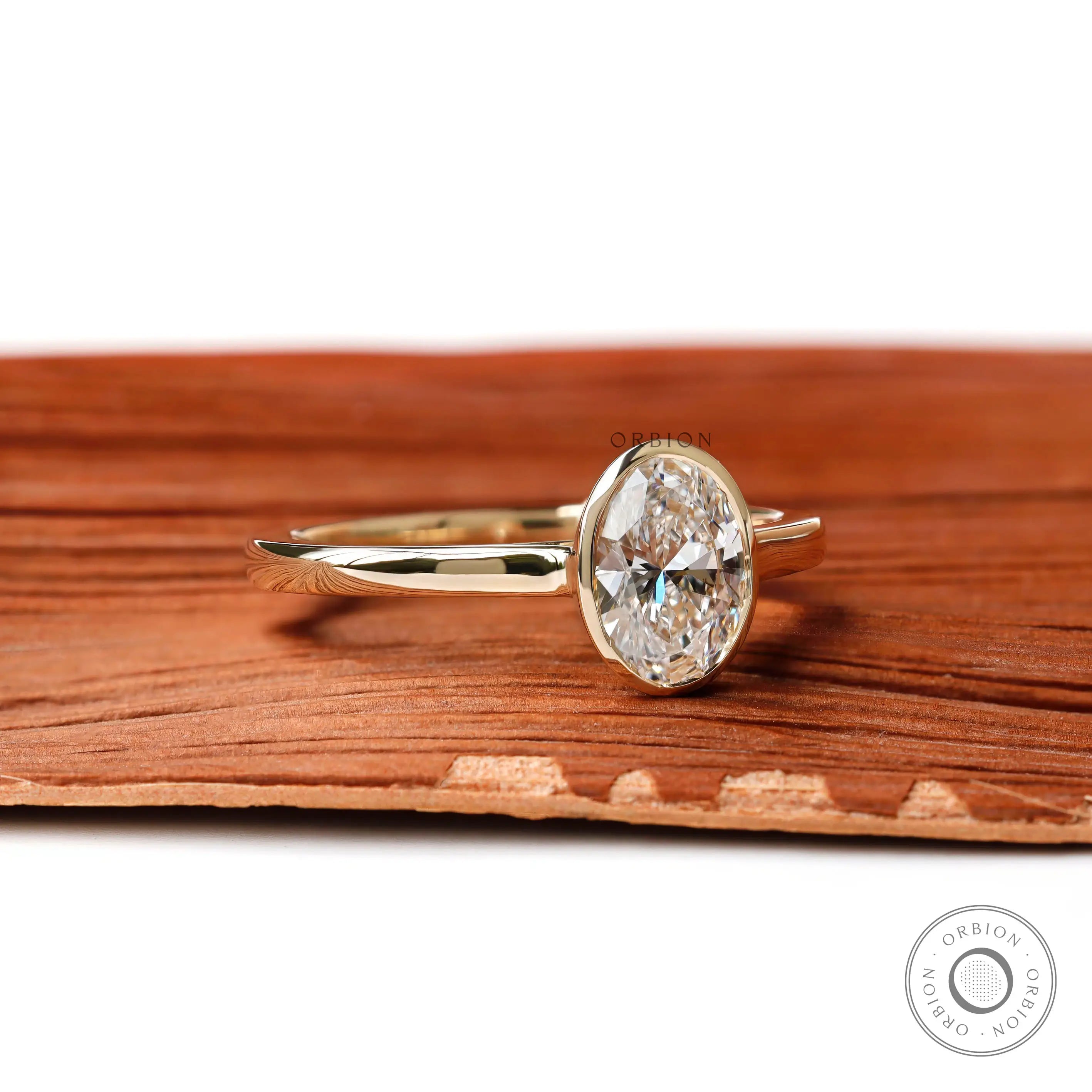 Angled view of oval bezel lab diamond yellow gold ring
