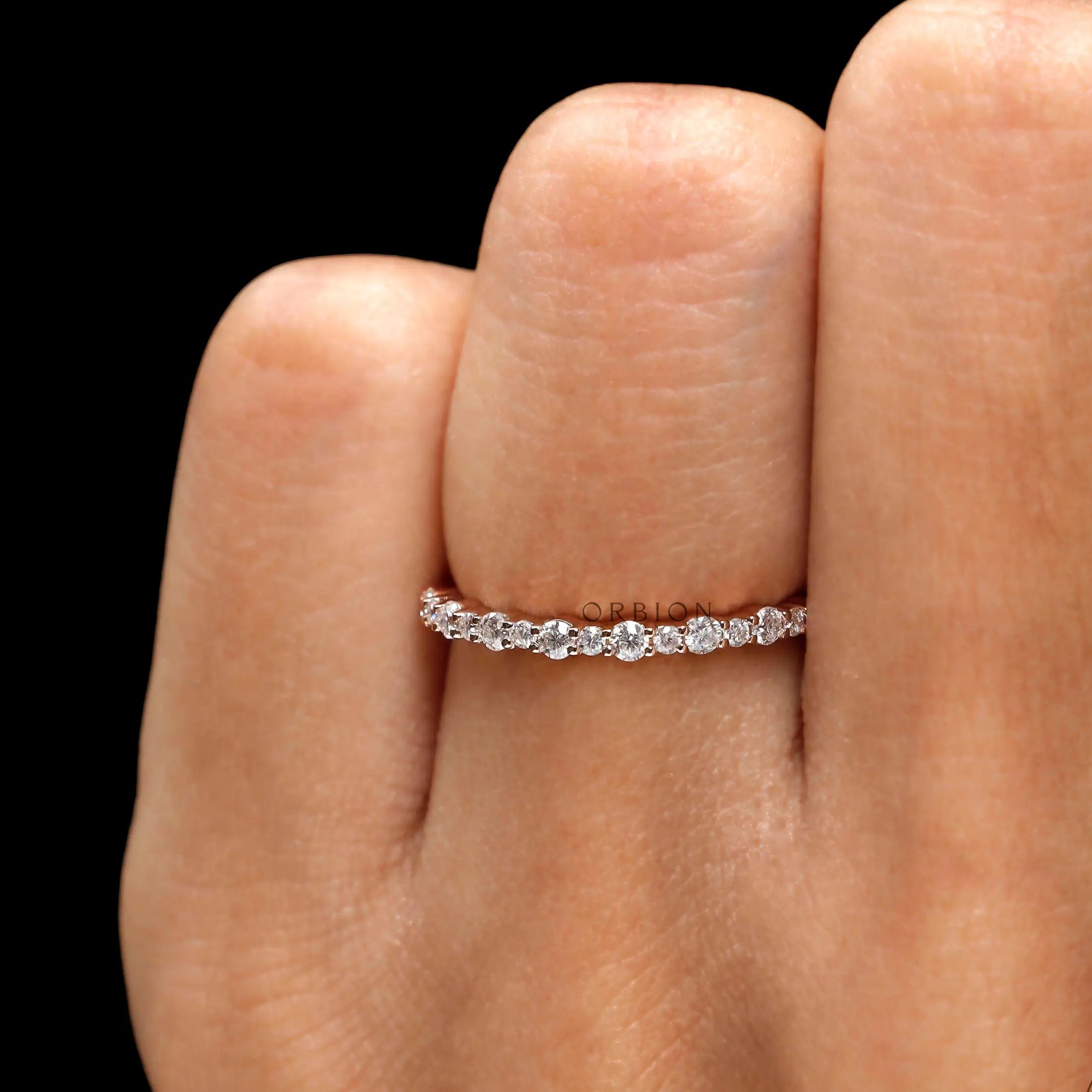 Dainty moissanite wedding band worn on finger