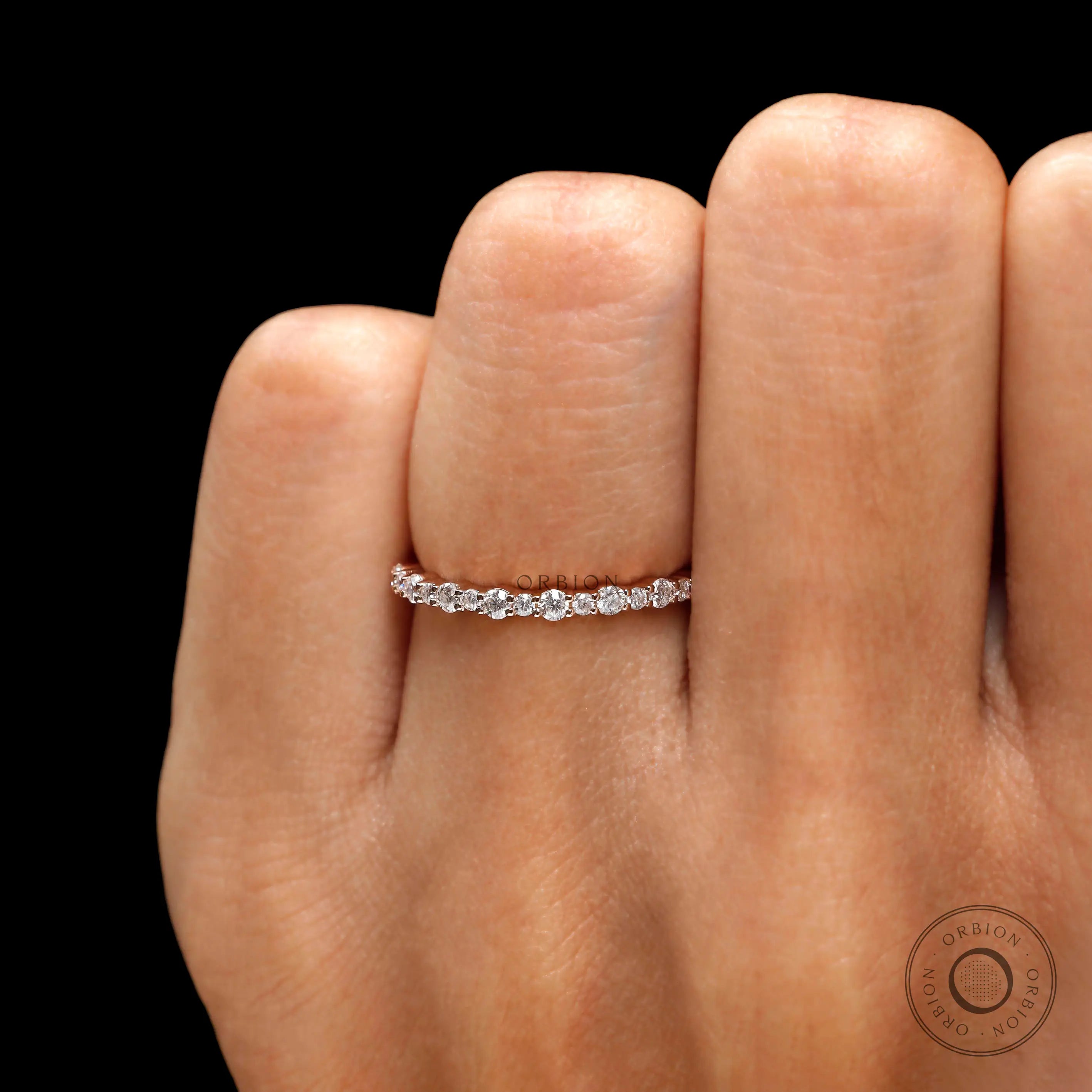 Dainty moissanite wedding band worn on finger