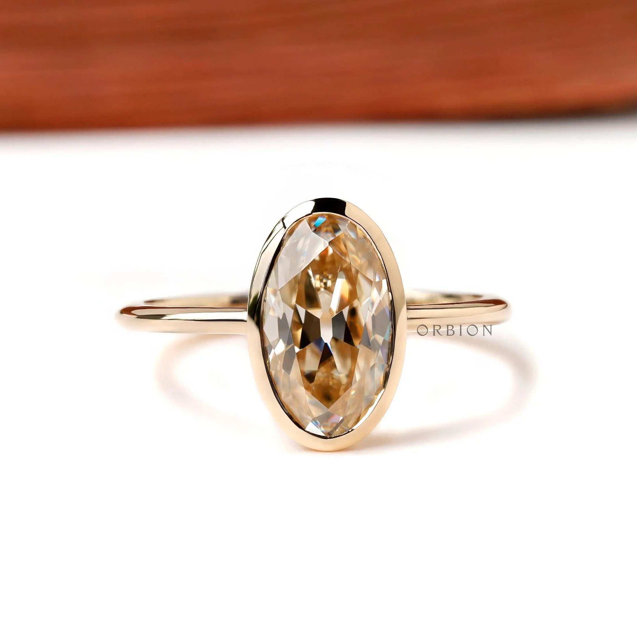 Front view oval champagne bezel ring in yellow gold on white background