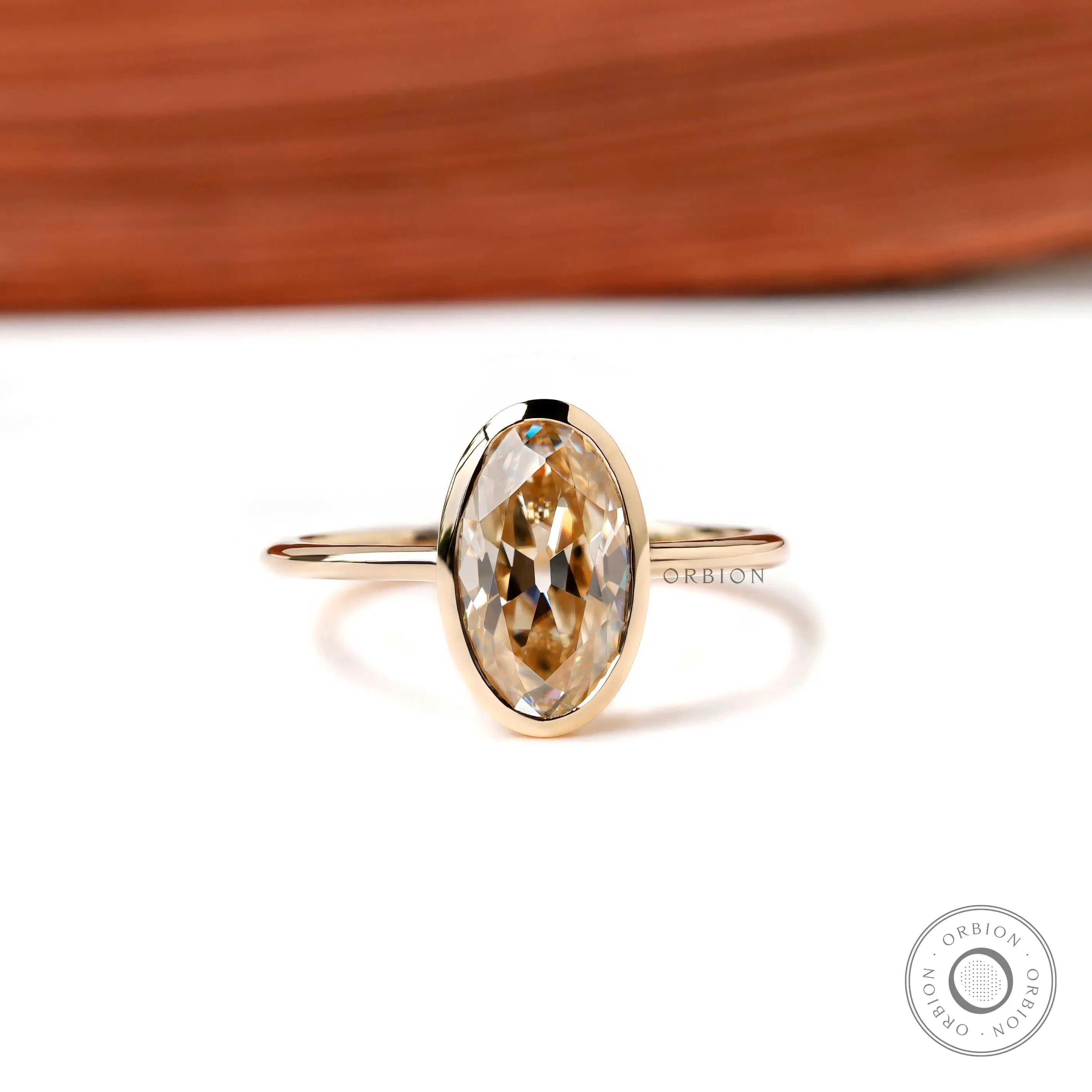 Front view oval champagne bezel ring in yellow gold on white background