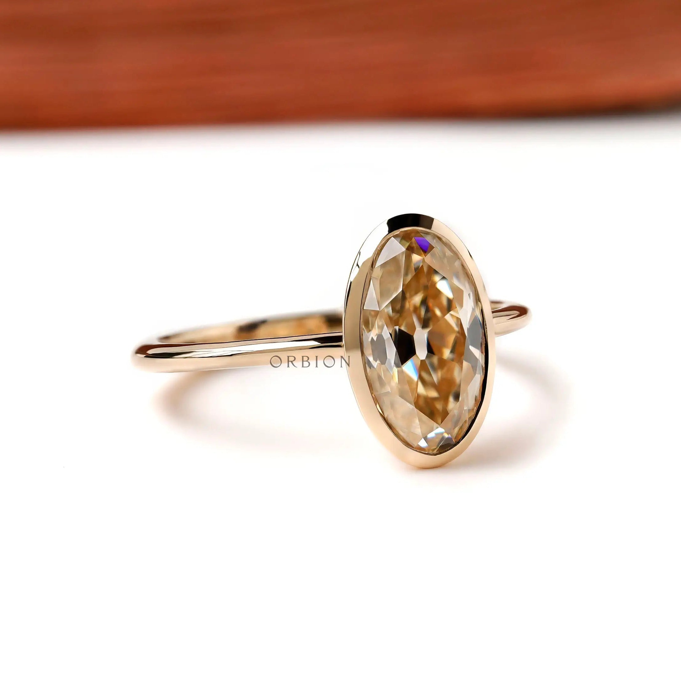 Angled view oval champagne bezel solitaire ring in yellow gold