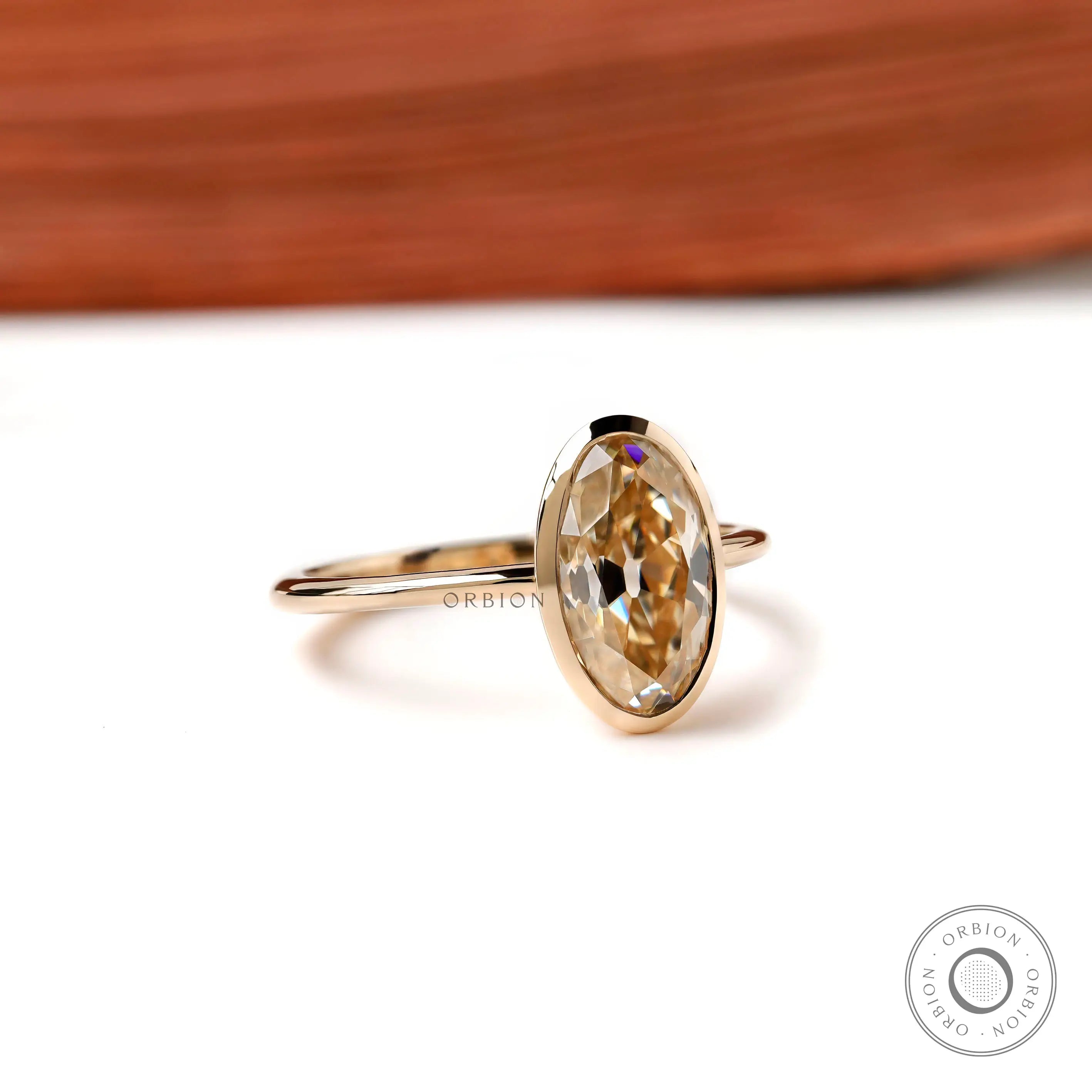Angled view oval champagne bezel solitaire ring in yellow gold