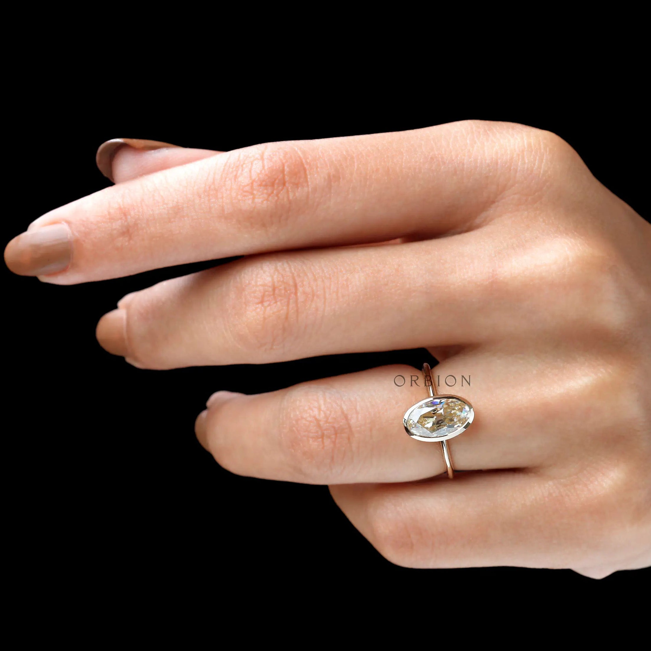On hand lifestyle view oval champagne bezel ring in yellow gold