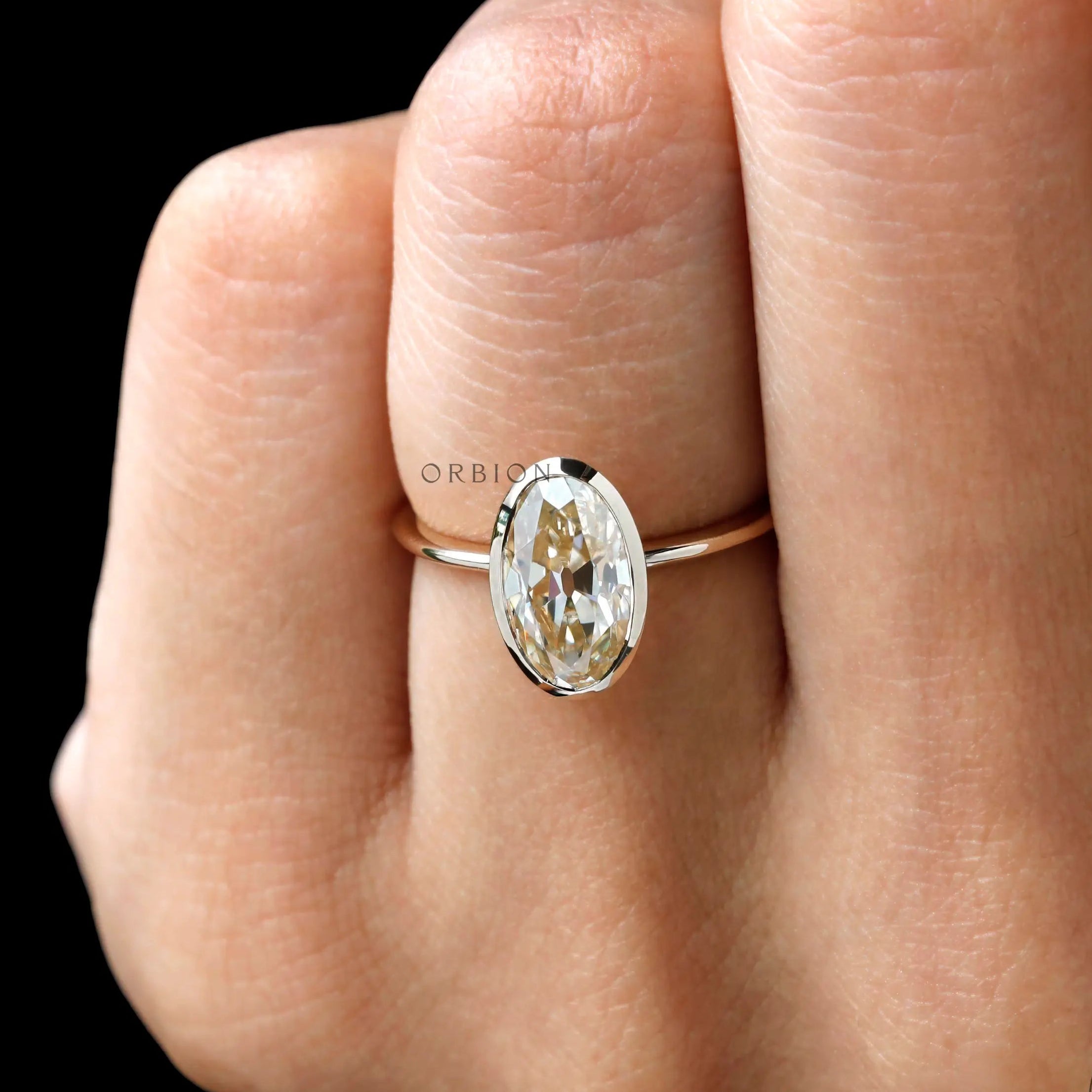 Closeup on finger oval champagne stone in smooth bezel frame