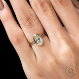 Angled closeup on hand oval champagne bezel ring in yellow gold