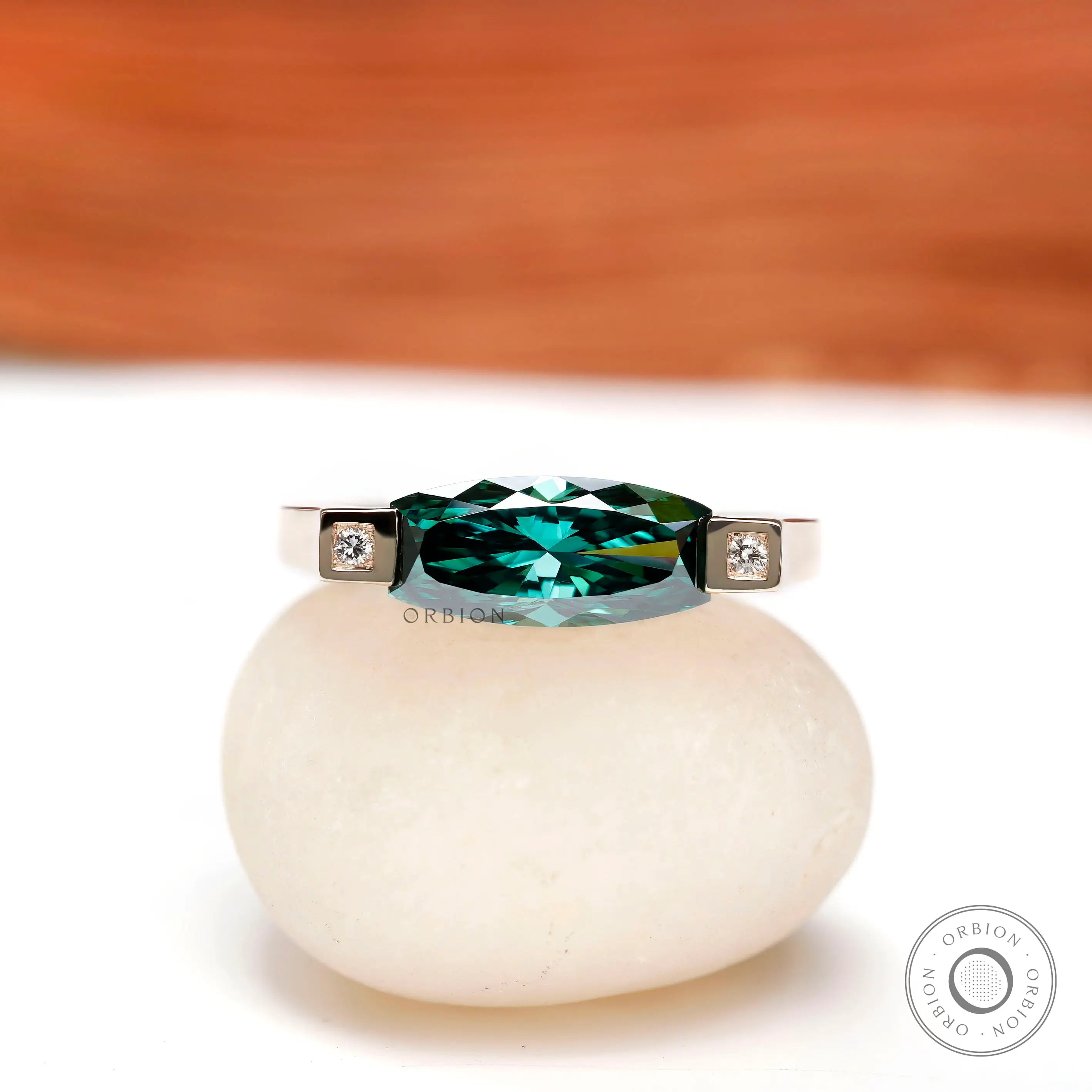 Front view of east west blue green ring with square bezel-set diamond accents in yellow gold.
