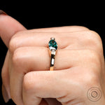 On-hand top view displaying blue green marquise center with square bezel diamond accents.