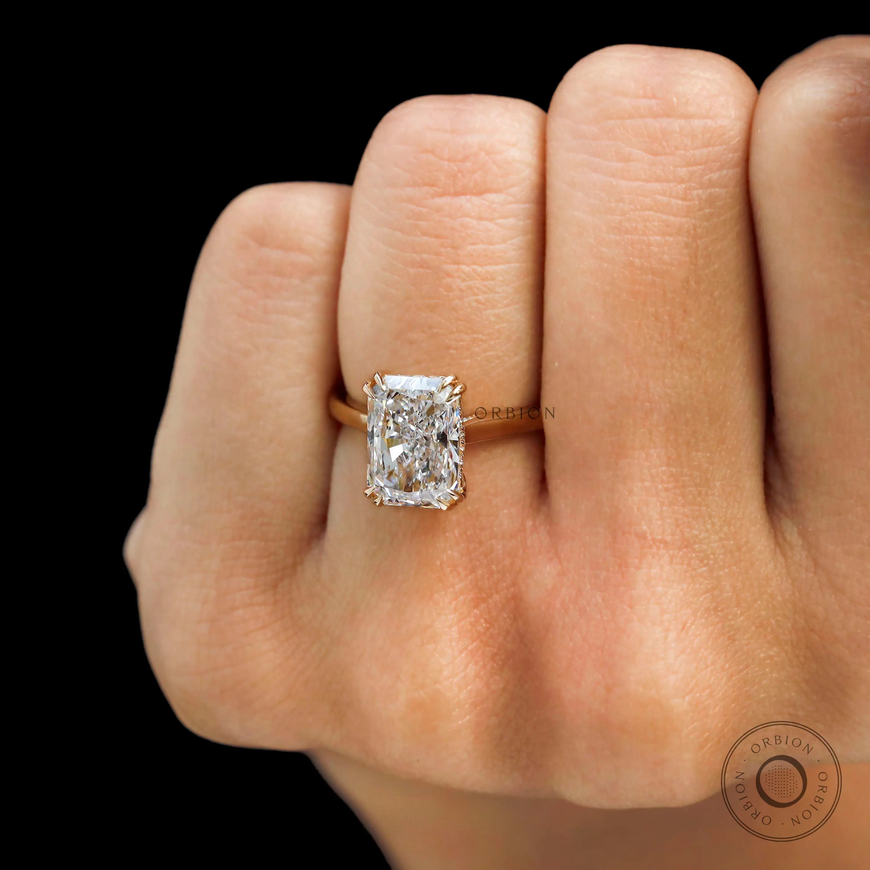 Radiant cut lab diamond solitaire engagement ring on finger close up