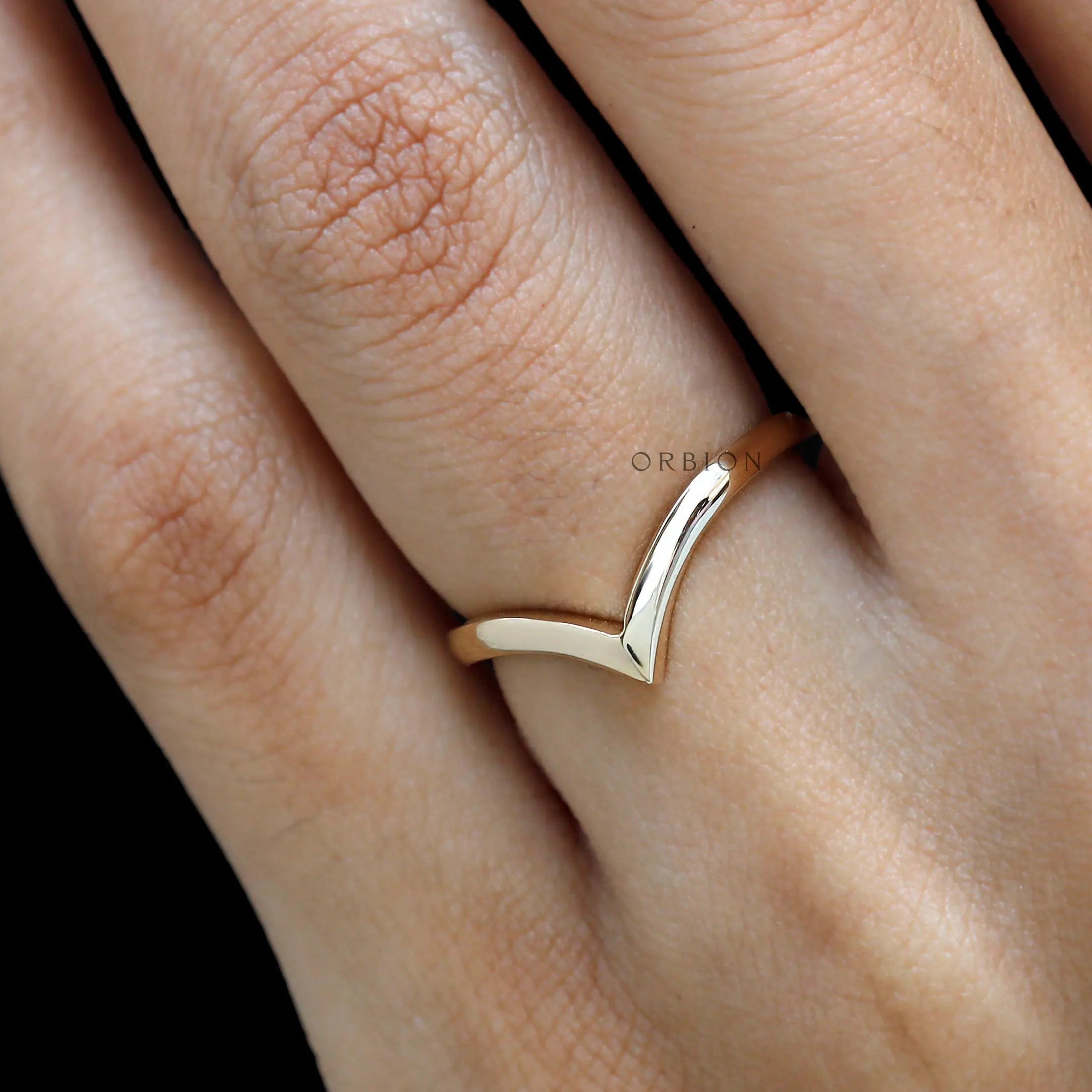 Close-up on hand featuring sleek chevron wedding band.