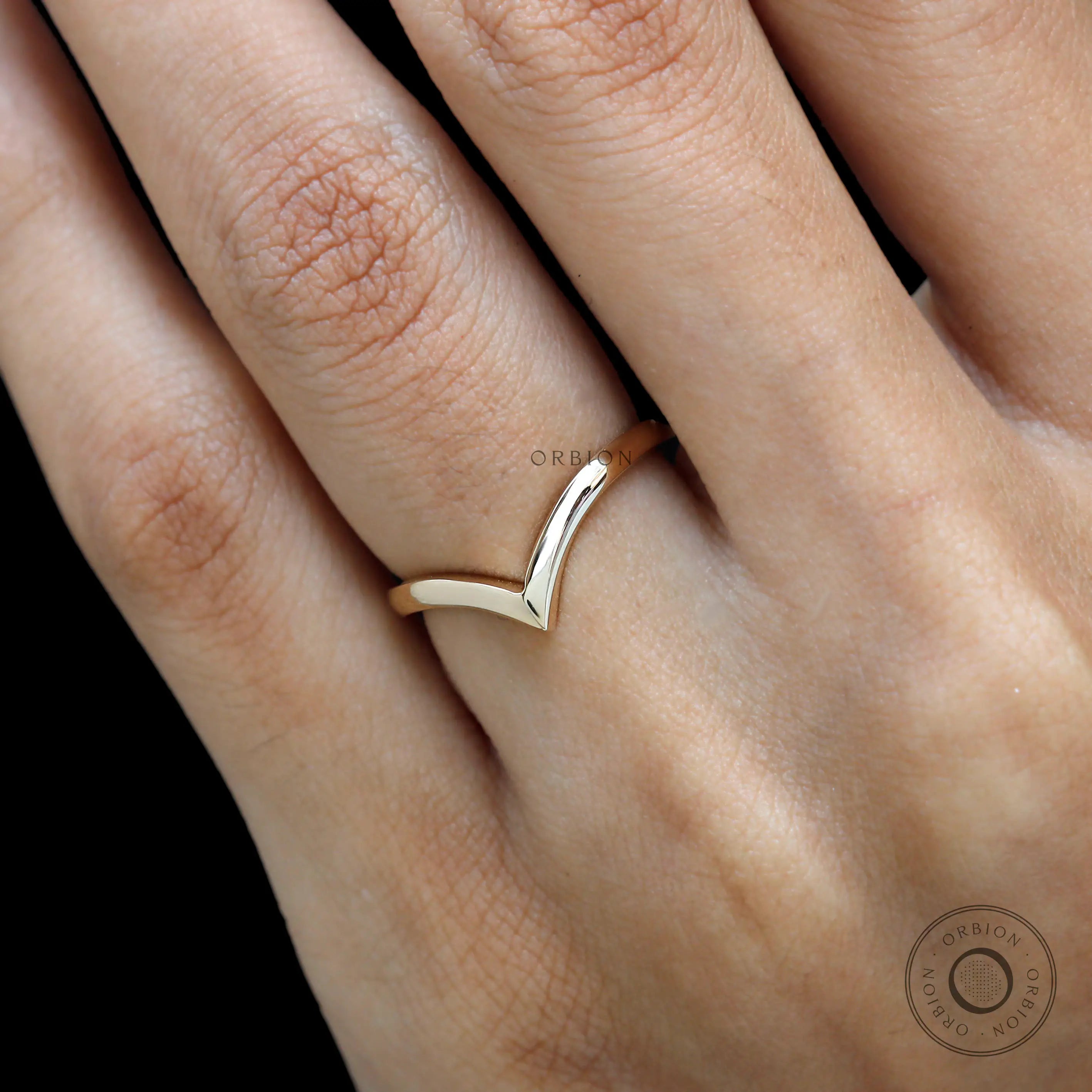 Close-up on hand featuring sleek chevron wedding band.