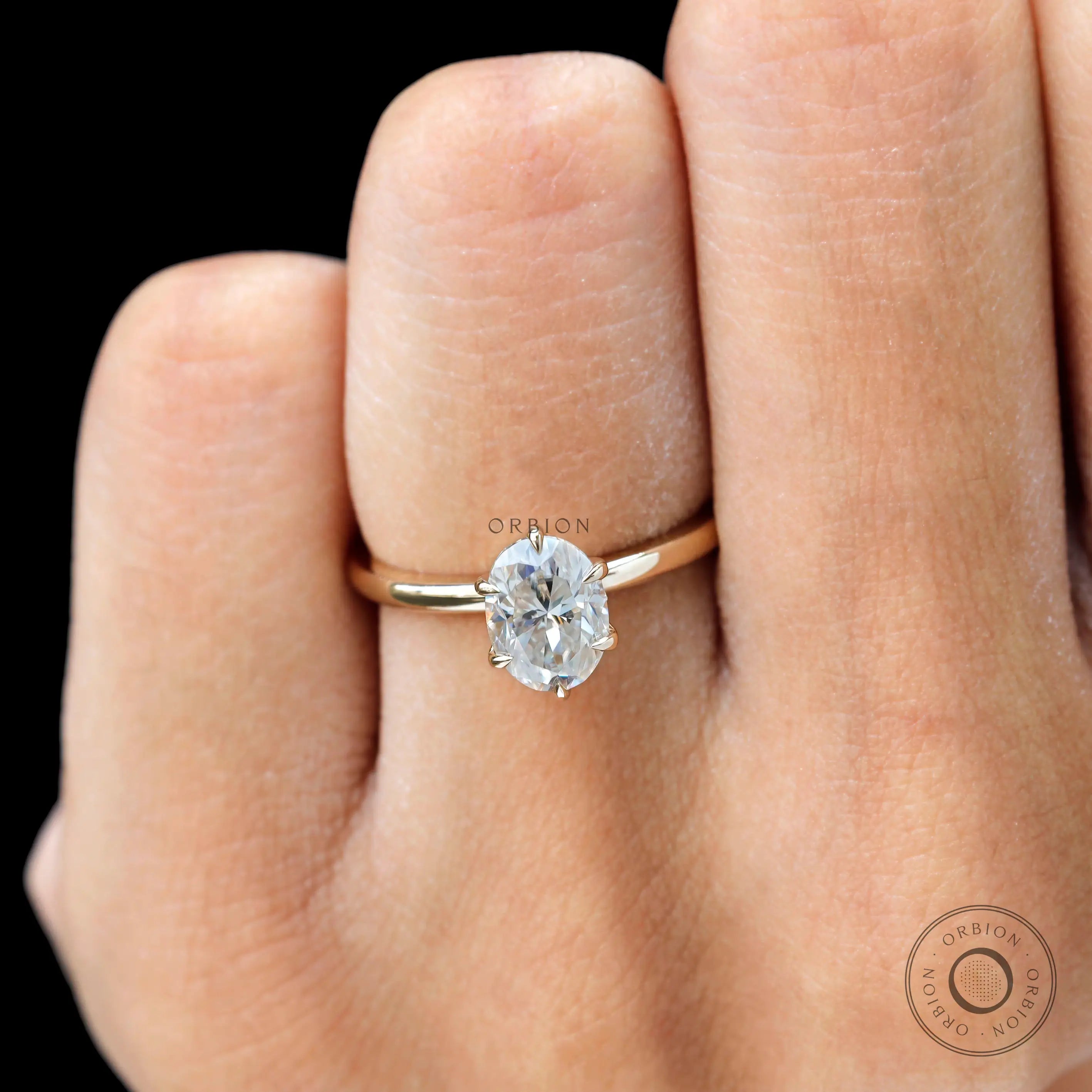 Close on-hand view of oval moissanite sparkle with six prongs.