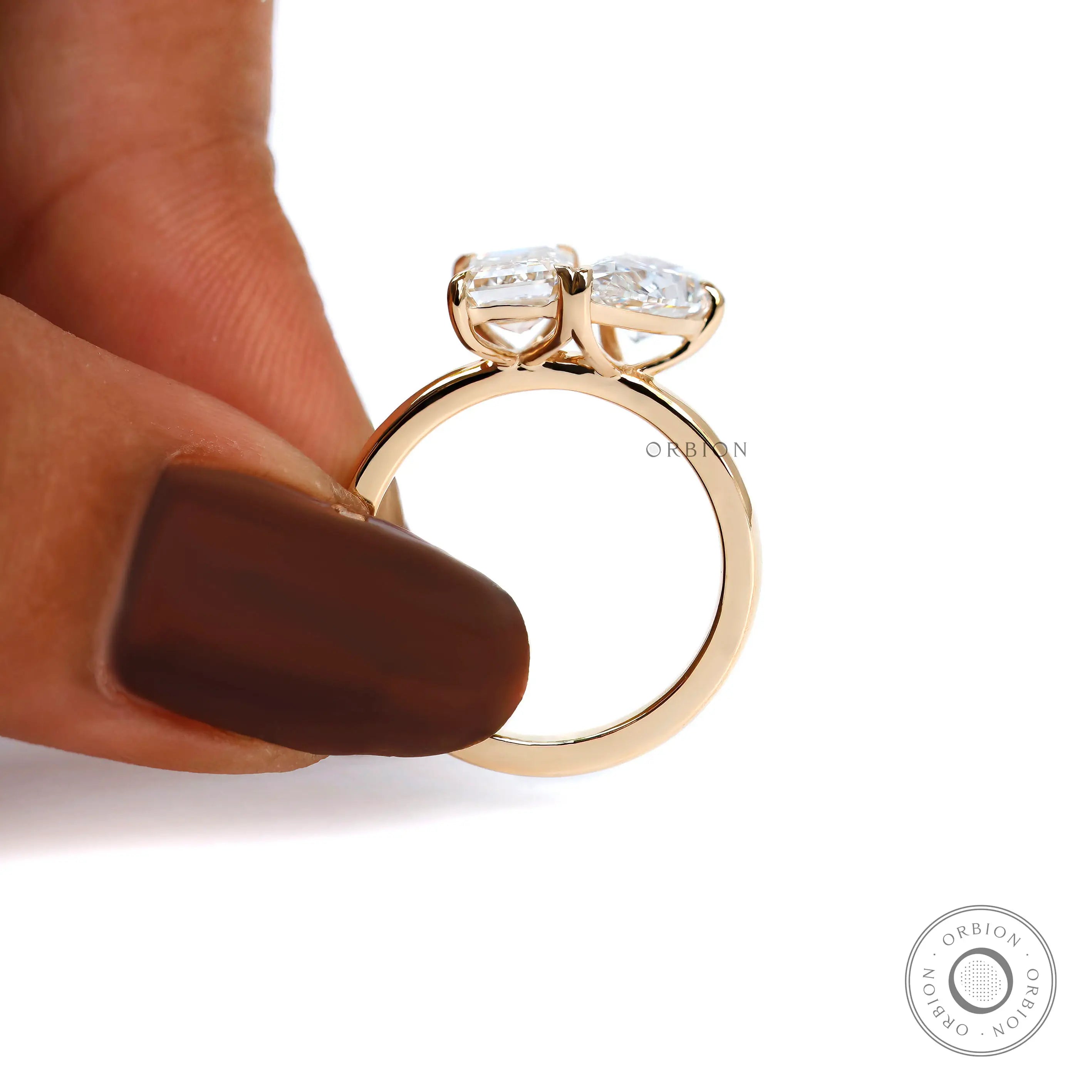Top view on fingers showing balanced pear and emerald stone placement.