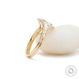 Split shank oval moissanite ring leaning on white stone