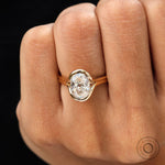 Oval moissanite half bezel ring worn on finger top view