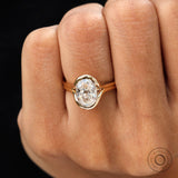 Oval moissanite half bezel ring worn on finger top view