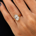 Angled on-hand shot of floating oval moissanite bezel ring